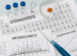 Laboratory setup showing vials, a pipette, chromatogram graphs, and calibration curve charts representing precision and reproducibility in metabolomics internal standards research at IROA Technologies.