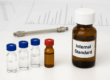 Laboratory glass vials and an amber bottle labeled “Internal Standard” representing internal standard sets used for accurate metabolomic analysis in a research lab.